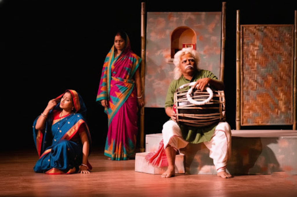 Bengali theatre artists performing on a Kolkata stage as part of Aneek’s cultural initiative, featuring traditional costumes and live folk music.