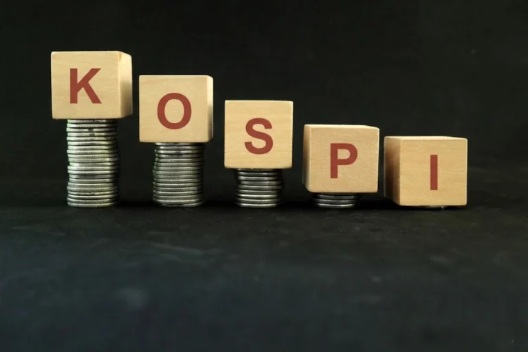 Wooden blocks spelling KOSPI placed on stacks of coins in descending order symbolizing Koshpi index crash impact on India and stock market decline
