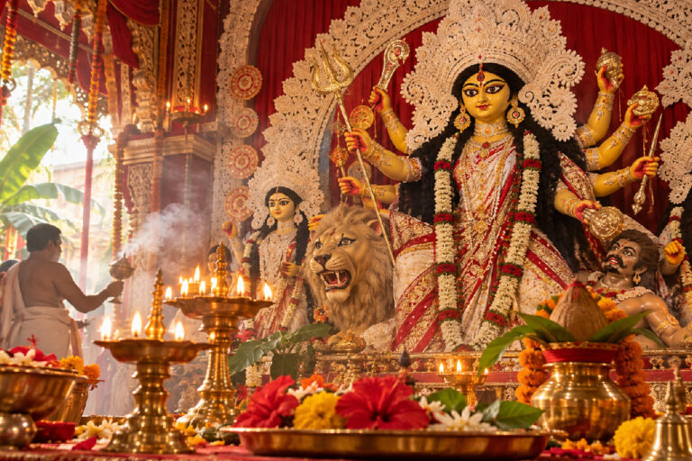 অষ্টমীর অঞ্জলি এবারও কী ভোরে দিতে হবে? শেষ কবে এমন ঘটনা ঘটেছিল? : Durga Puja 2026 Timings illustrated with Goddess Durga, flowers and traditional puja lamps.