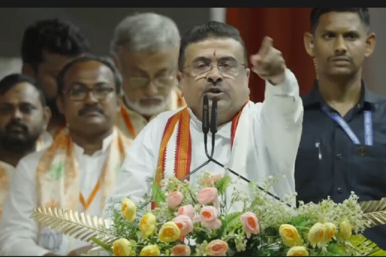 ‘বড় চোরও যাবে, ধৈর্য ধরুন!’ মমতা-অভিষেককে তীব্র আক্রমণ শুভেন্দুর, আর কী বললেন? Suvendu Adhikari Attacks Mamata Banerjee – Editorial image of Suvendu Adhikari addressing a political gathering, representing his criticism of Mamata Banerjee and Abhishek Banerjee over post-poll violence, corruption allegations and West Bengal politics.